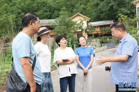 中国银行湖北省分行驻盘龙村帮扶工作队队长曲宏（右一）向游客介绍迴龙坪旅游发展状况。新华网连迅 摄